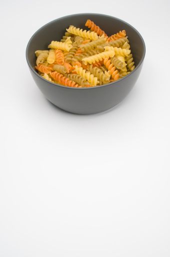 A vertical shot of tri-color rotini pasta on a bowl isolated on white background
