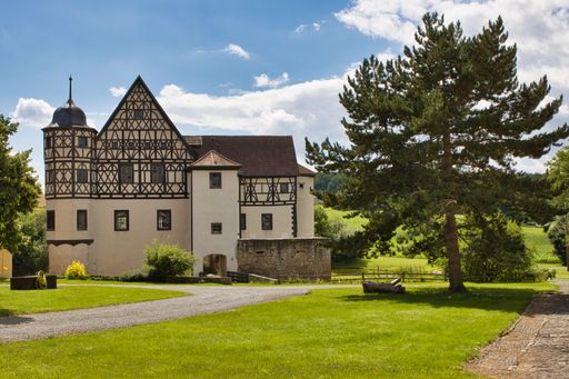 An antique white house in the greenery on a sunny day