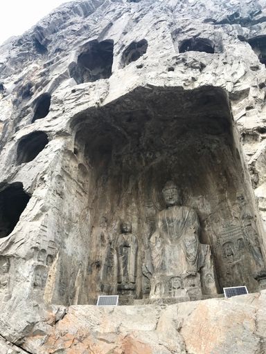 Ancient Buddhist rock carvings at Longmen Grottoes, China, showcasing intricate sculptures in a natural cave setting.