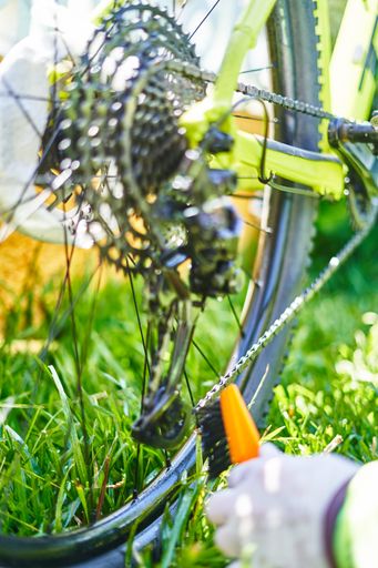 A vertical closeup shot of a male in gloves fixing a bicycle's brake pad