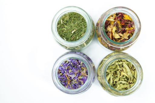 A top view of glass jars with medicinal plants on white background and copy space ,naturopathic concept