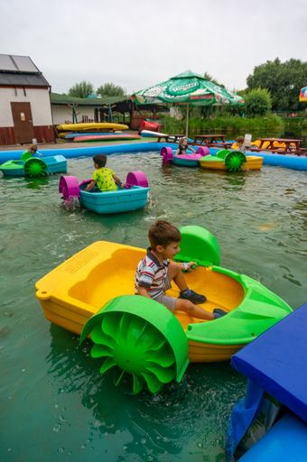 A vertical shot of kids having fun on plastic small boats in the pool in the Nenufar Club entertainment park