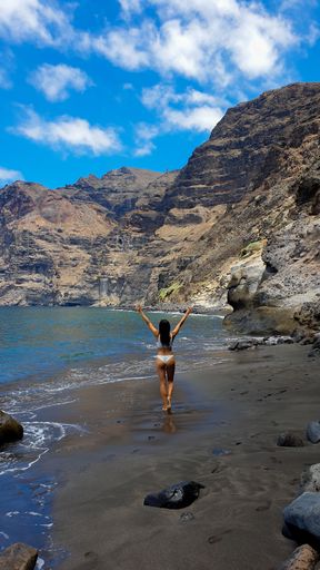A vertical shot of a Hispanic woman enjoying her vacation on the beach