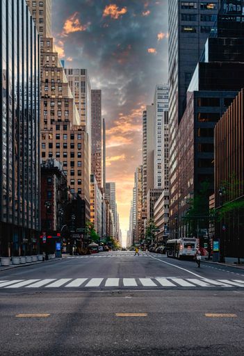 A vertical shot of a street surrounded by skyscrapers under the colorful skies