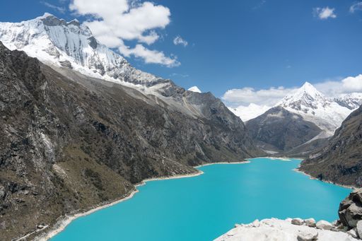Scenic view of turquoise lake surrounded by snow-capped mountains under a clear blue sky in the Andes.