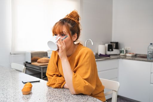 A closeup shot of a caucasian female drinking tea in a kitchen