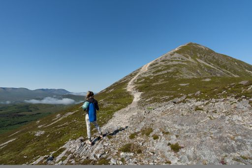 A scenic view of a young mountaineer woman climbing the Croagh Patrick mountain