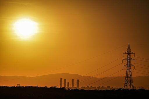 Horizontal image of the Madrid skyline in an orange sunset, with a high voltage electrical tower.