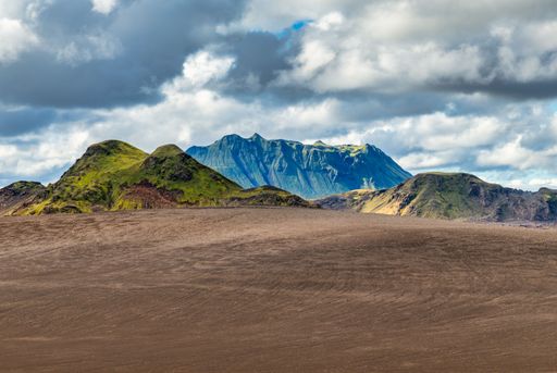 A scenic view of Icelandic mountains with vibrant green moss under a cloudy sky.