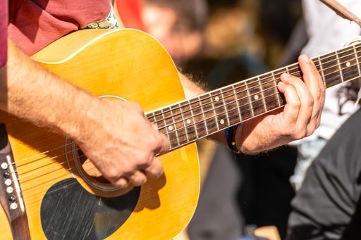 close-up of guitarist's hand on fretboard, a man playing the Spanish guitar at an outdoor event