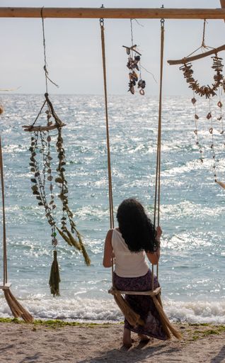 A closeup shot of a landscape with a female on the swing by the seaside