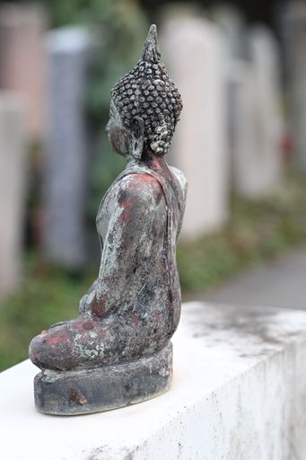 A weathered Buddha statue in a serene outdoor setting, showcasing intricate details and a peaceful ambiance.