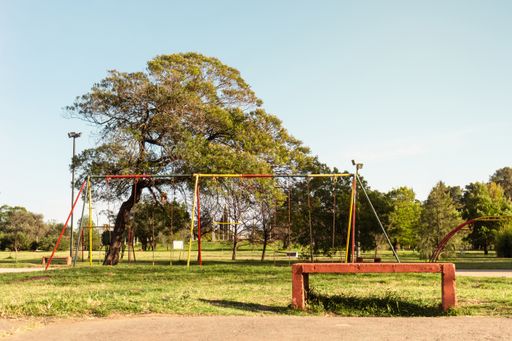 An empty bench in the park with games for children on a sunny day