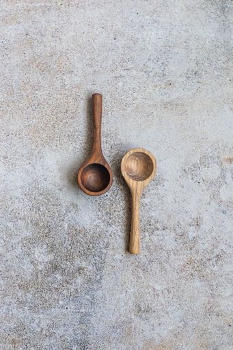 Two wooden measuring spoons on a textured stone background, showcasing rustic kitchenware style.