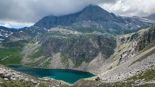 An aerial shot of a beautiful lake at the base of a mountain range at the Gran Paradiso Natural Reservation in Italy