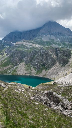 An aerial shot of a beautiful lake at the base of a mountain range at the Gran Paradiso Natural Reservation in Italy