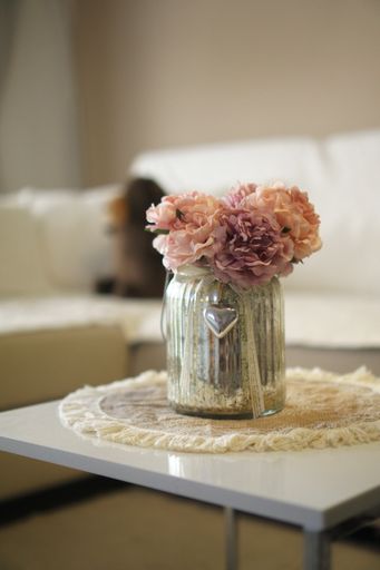 A vertical shot of artificial peony flowers in a glass vase indoors