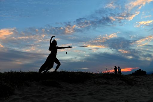 A silhouette of a woman practising Taichi-Kwon at the beach during the sunset in Busan, South Korea