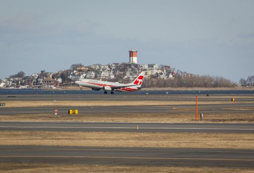 American Airlines plane with retro TWA livery takes off at Boston's Logan Airport on a sunny day