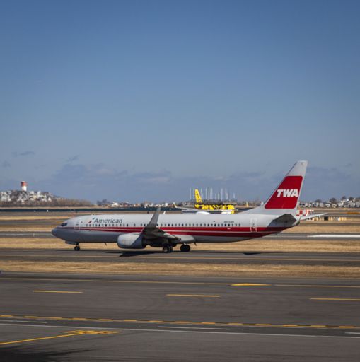 American Airlines plane with retro TWA livery taxis at Boston Logan Airport on a sunny day