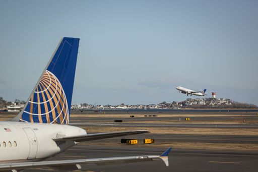 United Airlines plane at Logan Airport with another plane taking off in the background
