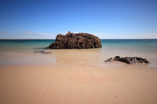 A beautiful view rock formation on the beach against a blue sky on a sunny day