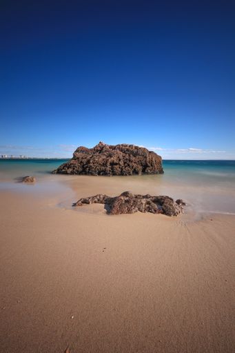 A beautiful view rock formation on the beach against a blue sky on a sunny day