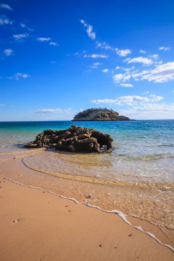 A vertical shot of a beach, an island in the distance