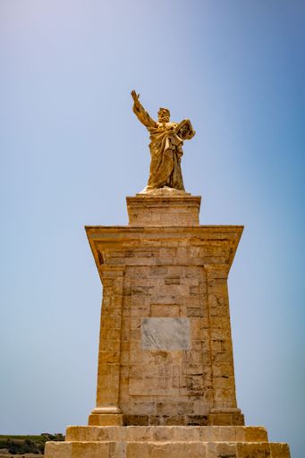 Majestic statue of Saint Paul on St. Paul Island, Malta, symbolizing faith and history under a clear blue sky.