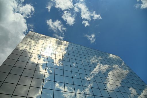 A low angle shot of a modern building glass facade reflecting the clouds in Tur in Italy