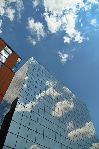 A vertical shot of a modern building glass facade reflecting the clouds in Tur in Italy