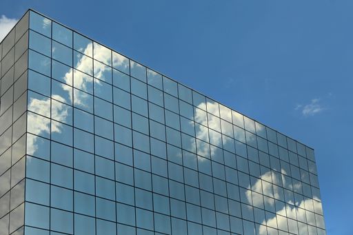 A low angle shot of a modern building glass facade reflecting the clouds in Tur in Italy