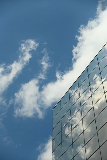 A vertical shot of a modern building glass facade reflecting the clouds in Tur in Italy