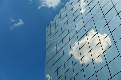 A low angle shot of a modern building glass facade reflecting the clouds in Tur in Italy
