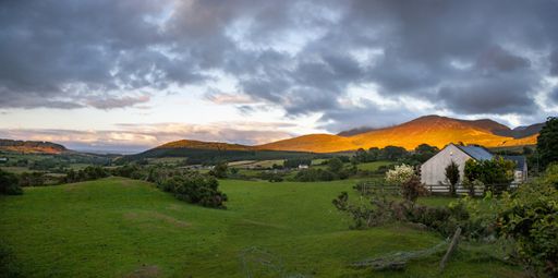 A landscape of a rural area on the Mourne Mountains under a cloudy sky in Northern Ireland