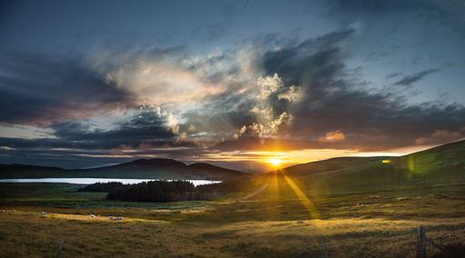 The Mourne Mountains covered in greenery under a cloudy sky during the sunset in Northern Ireland