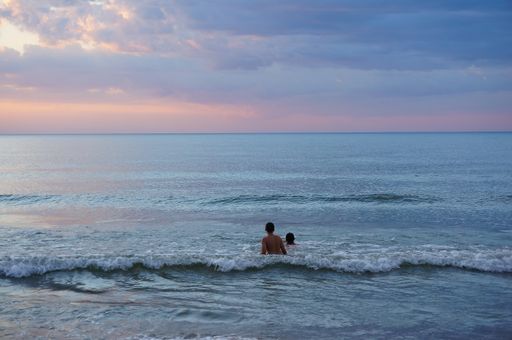 Two people swimming in the water at a beach of Sarbinowo, Poland in the evening