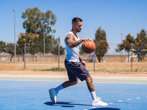 An athletic handsome Spanish basketball player training on a basketball court