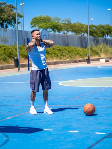 An athletic handsome Spanish basketball player training on a basketball court