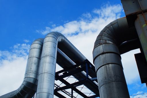 District heating pipes at a combined heat and power plant in Frankfurt, Germany. Blue sky and clouds.
