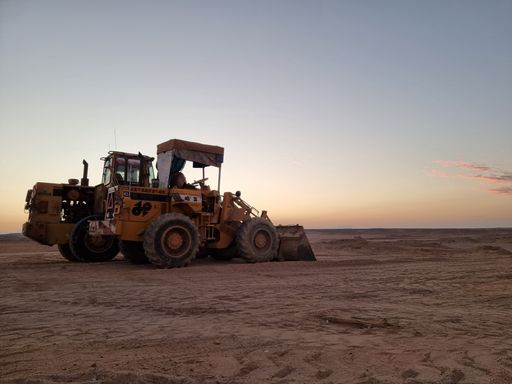 A construction bulldozer at sunset on a vast desert landscape, capturing the serene and rugged environment.