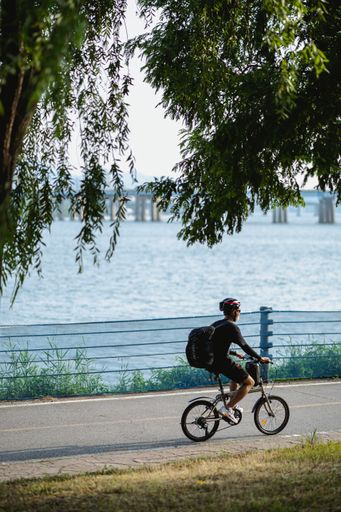 A vertical shot of a man riding a bicycle near a lake