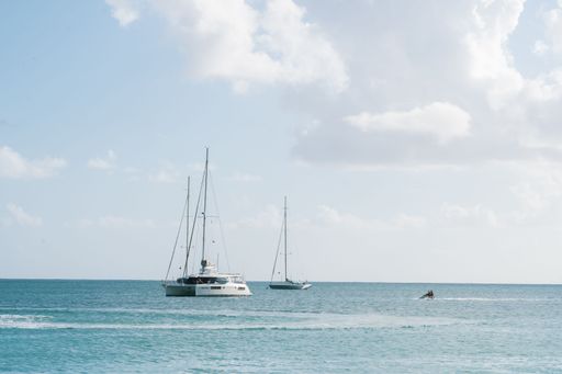 Sailboats and a jet ski on a calm sea under a partly cloudy sky, capturing a serene marine scene.