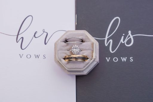 Elegant wedding rings in a velvet box with his and her vows in the background.