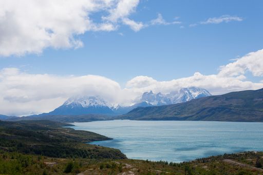 Scenic view of Torres del Paine mountains and a tranquil lake under a bright blue sky in Patagonia, Chile.