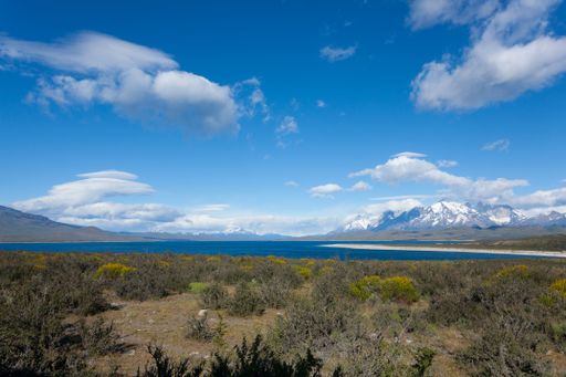 Scenic view of Torres del Paine National Park with snow-capped mountains, blue lake, and vibrant sky in Patagonia, Chile.