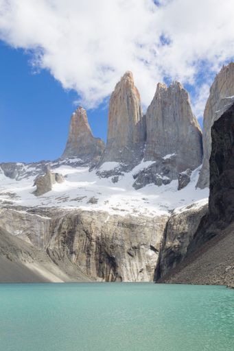Scenic view of the Torres del Paine peaks with a turquoise lake under a bright blue sky in Patagonia, Chile.
