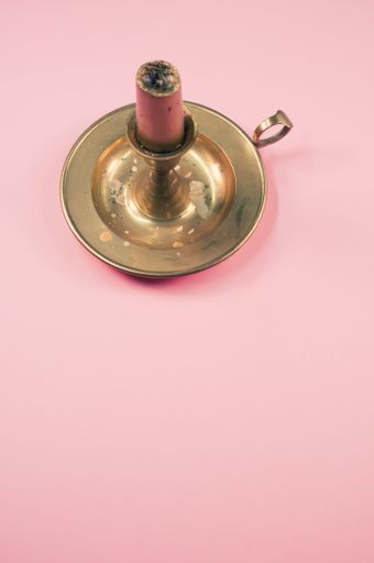 A candleholder with pink candle isolated on a pink background with free space for text