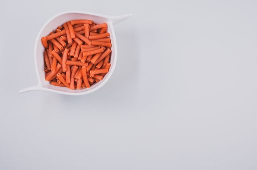 A bowl of dry macaroni pasta isolated on a white background with free space for text