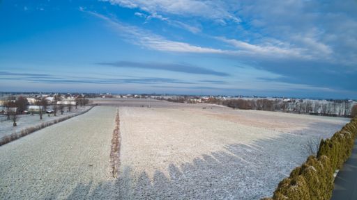 A high angle shot of an empty field under a blue cloudy sky